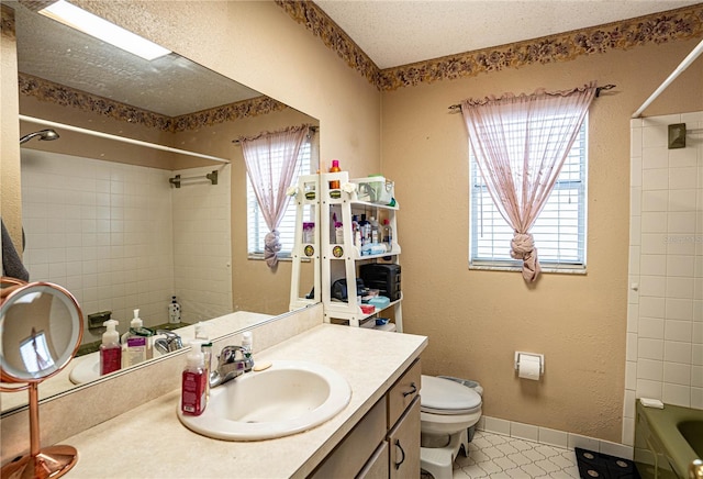 full bathroom with tiled shower / bath combo, vanity, a textured ceiling, and toilet