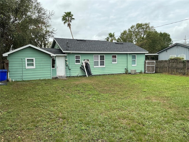 rear view of house featuring central AC unit and a lawn