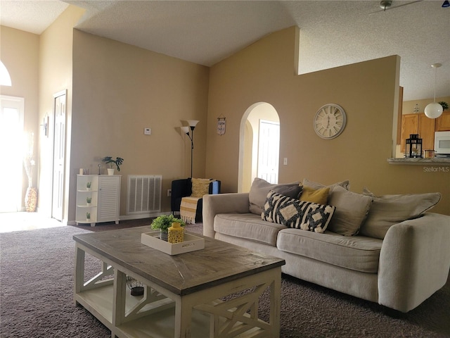 living room with dark colored carpet, a textured ceiling, and high vaulted ceiling