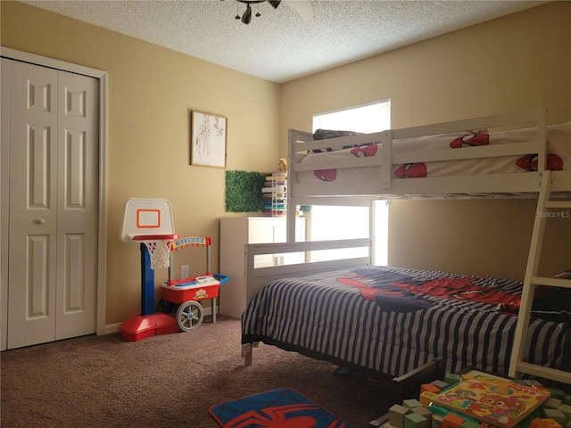 carpeted bedroom with a closet, ceiling fan, a textured ceiling, and multiple windows