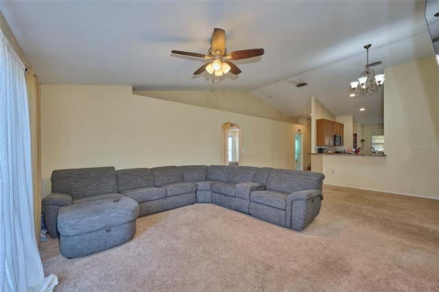 living room with vaulted ceiling, light colored carpet, and ceiling fan with notable chandelier