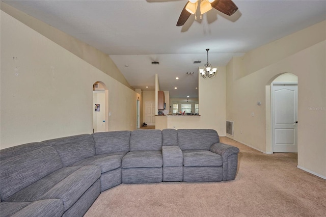 living room with ceiling fan with notable chandelier, light carpet, and vaulted ceiling