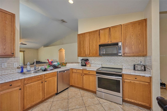 kitchen with stainless steel appliances, backsplash, light tile patterned floors, sink, and lofted ceiling