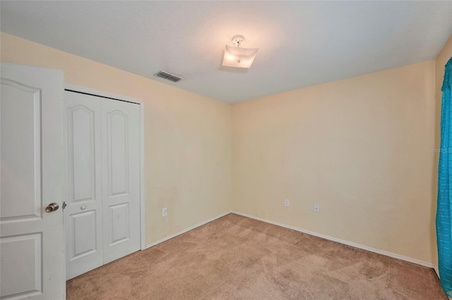 unfurnished bedroom featuring a closet and light colored carpet