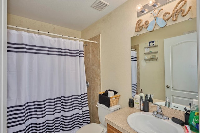 bathroom featuring curtained shower, vanity, toilet, and a textured ceiling