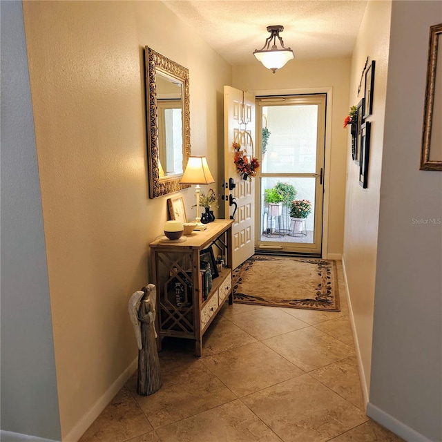 doorway with a textured ceiling and light tile patterned floors