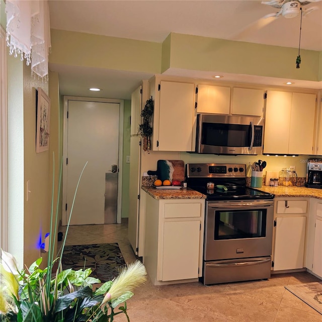 kitchen featuring appliances with stainless steel finishes, light stone countertops, ceiling fan, light tile patterned floors, and white cabinets