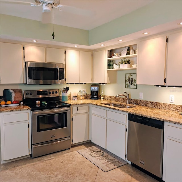 kitchen with white cabinets, appliances with stainless steel finishes, sink, and light stone countertops