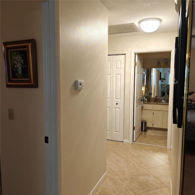 hallway featuring light tile patterned flooring and a textured ceiling