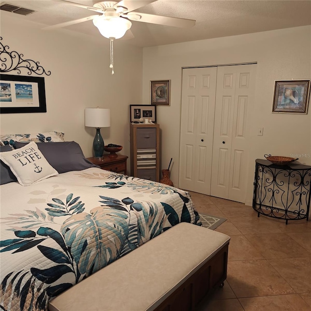 tiled bedroom with ceiling fan and a closet