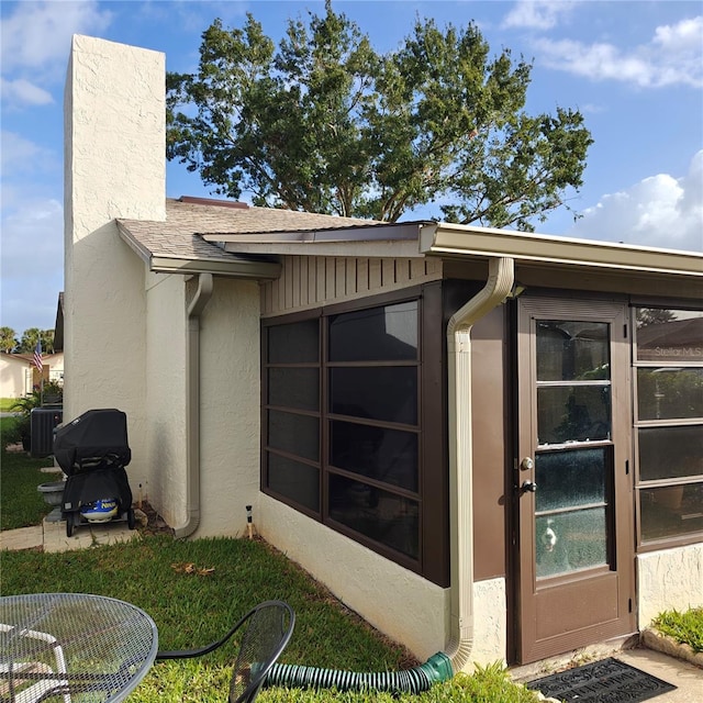 view of property exterior with central AC unit and a sunroom