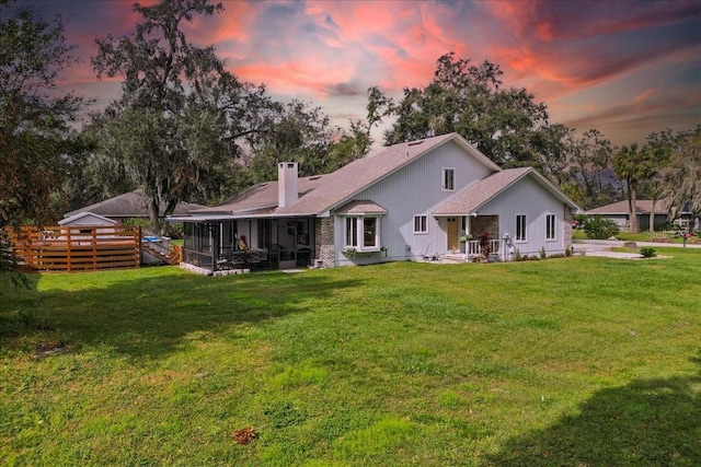 back house at dusk with a lawn