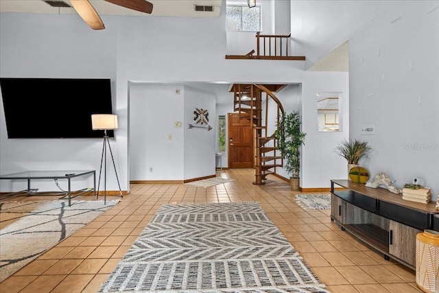 entryway featuring a towering ceiling, light tile patterned flooring, and ceiling fan