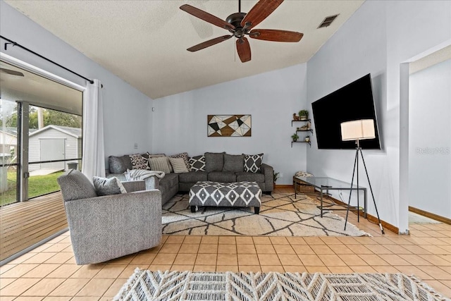 living room with ceiling fan, lofted ceiling, a textured ceiling, and light tile patterned flooring