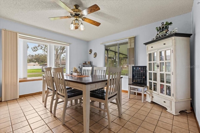 tiled dining area featuring a textured ceiling and ceiling fan