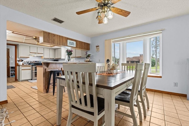 tiled dining area with a textured ceiling and ceiling fan