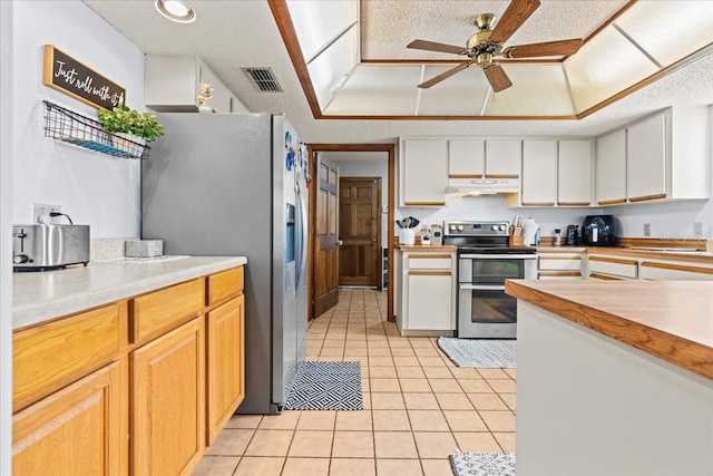 kitchen featuring stainless steel appliances, a textured ceiling, light tile patterned floors, and white cabinets