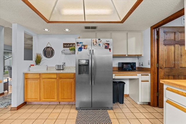 kitchen with stainless steel fridge, a textured ceiling, and light tile patterned floors