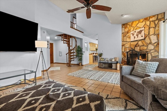 tiled living room featuring a stone fireplace, high vaulted ceiling, a textured ceiling, and ceiling fan