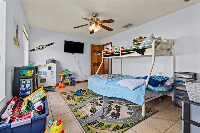 tiled bedroom with a textured ceiling and ceiling fan