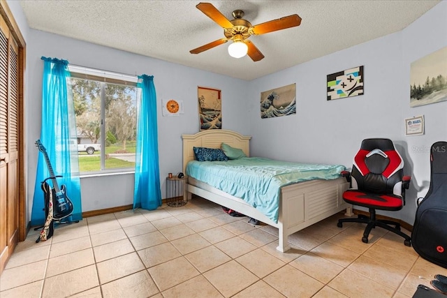 tiled bedroom with a textured ceiling, ceiling fan, and a closet