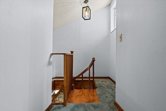 staircase with a textured ceiling, vaulted ceiling, and carpet floors