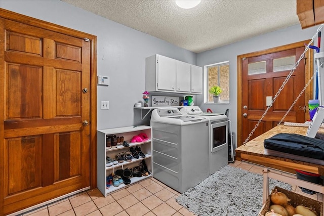 laundry area with cabinets, a textured ceiling, light tile patterned floors, and washer and clothes dryer