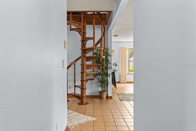 hall with a textured ceiling and light tile patterned flooring