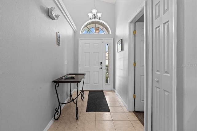 entryway with high vaulted ceiling, light tile patterned floors, and a notable chandelier