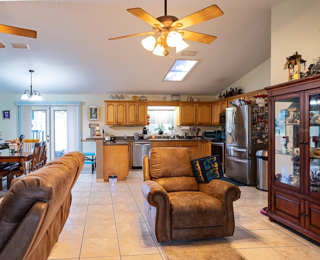 living room featuring ceiling fan with notable chandelier, high vaulted ceiling, light tile patterned floors, and a skylight