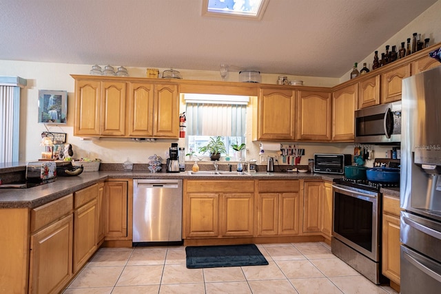 kitchen featuring stainless steel appliances, sink, a textured ceiling, light tile patterned floors, and lofted ceiling