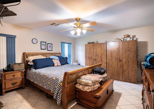 bedroom featuring light tile patterned flooring, ceiling fan, and a textured ceiling