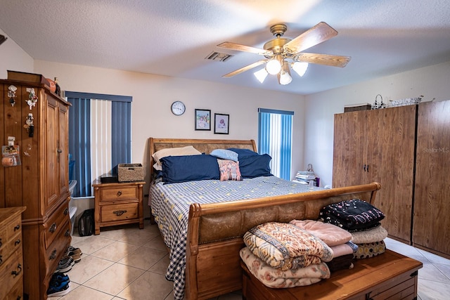 bedroom featuring light tile patterned flooring, ceiling fan, and a textured ceiling