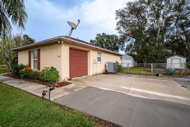 exterior space with a garage, cooling unit, and an outbuilding