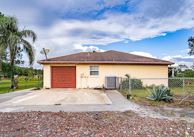 rear view of property featuring a garage and cooling unit