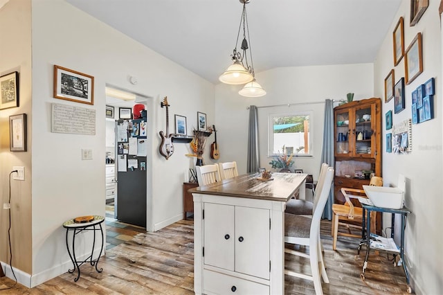 kitchen with hanging light fixtures, wood-type flooring, a breakfast bar, and white cabinets