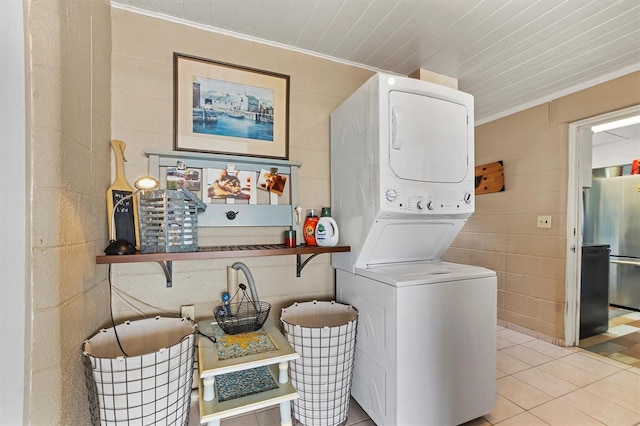 washroom with stacked washing maching and dryer, light tile patterned floors, and crown molding