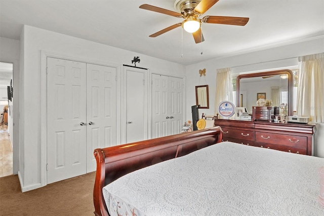 bedroom featuring multiple closets, ceiling fan, and dark carpet