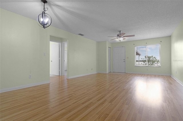 unfurnished living room featuring ceiling fan with notable chandelier, a textured ceiling, and light wood-type flooring