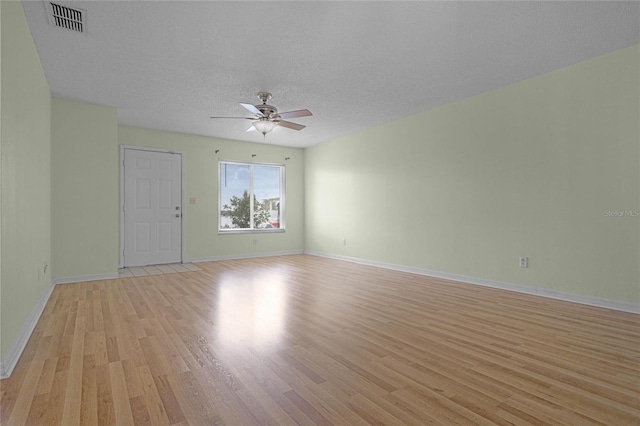 empty room with a textured ceiling, ceiling fan, and light hardwood / wood-style flooring