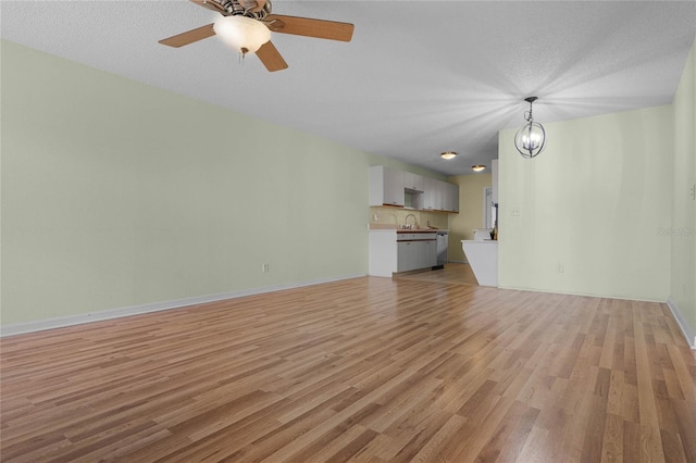 unfurnished living room with sink, a textured ceiling, and light hardwood / wood-style floors