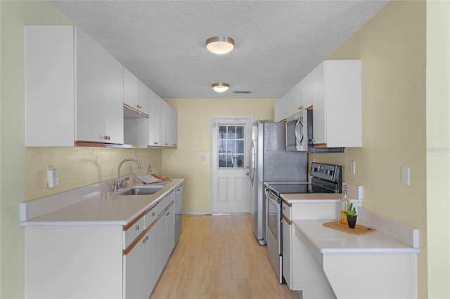 kitchen with stainless steel appliances, white cabinetry, a textured ceiling, sink, and light hardwood / wood-style floors