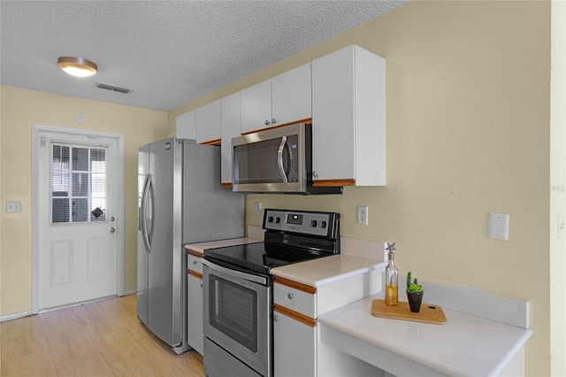 kitchen with appliances with stainless steel finishes, a textured ceiling, and white cabinets