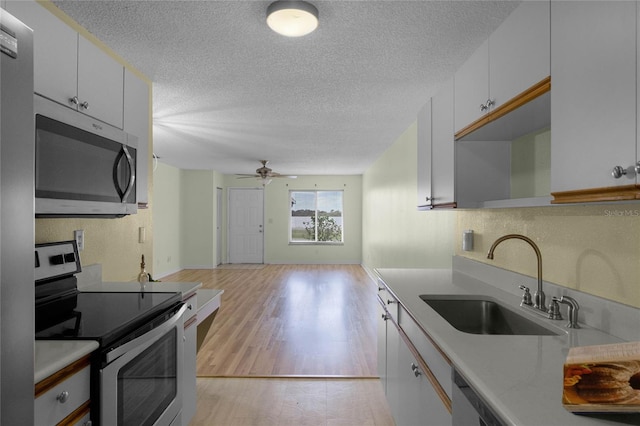 kitchen featuring white cabinetry, appliances with stainless steel finishes, sink, light hardwood / wood-style floors, and ceiling fan