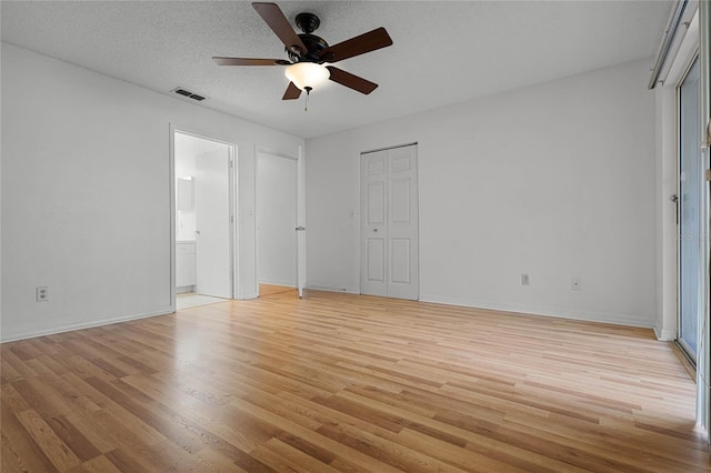 unfurnished bedroom with ensuite bathroom, light hardwood / wood-style flooring, a textured ceiling, and ceiling fan