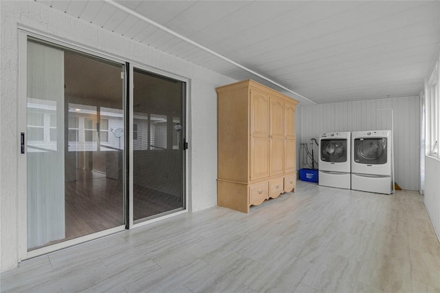 clothes washing area with washer and dryer and light hardwood / wood-style flooring