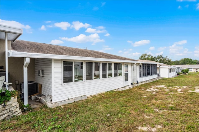 rear view of house featuring central AC unit, a lawn, and a sunroom