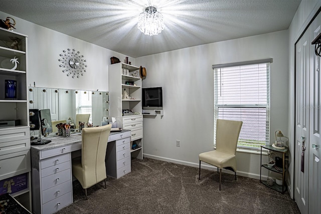 office space featuring an inviting chandelier, dark carpet, and a textured ceiling