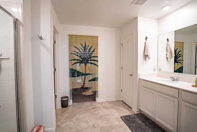 bathroom with vanity, a textured ceiling, and a shower with shower door