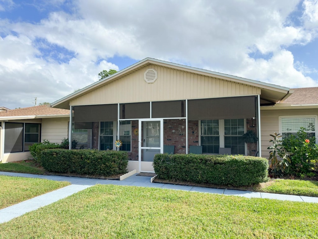 view of front facade with a front lawn and a sunroom